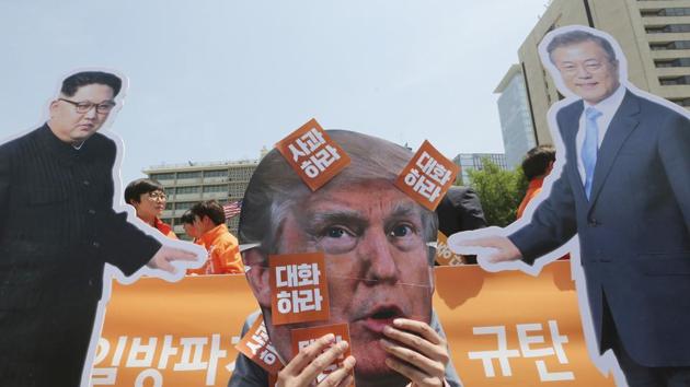 A protester wearing a mask of US President Donald Trump performs with cut-out photos of North Korean leader Kim Jong Un and South Korean President Moon Jae-in during a rally against the United States' policies against North Korea near the US embassy in Seoul, South Korea. (AP Photo) A protester wearing a mask of US President Donald Trump performs with cut-out photos of North Korean leader Kim Jong Un and South Korean President Moon Jae-in during a rally against the United States' policies against North Korea near the US embassy in Seoul, South Korea. (AP Photo)