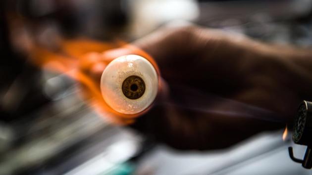 German ocularist and glass eye manufacturer Jan Mueller-Uri blows an artificial eye at his cabinet in Wiesbaden, Germany. (Andres Arnold / dpa / AFP)