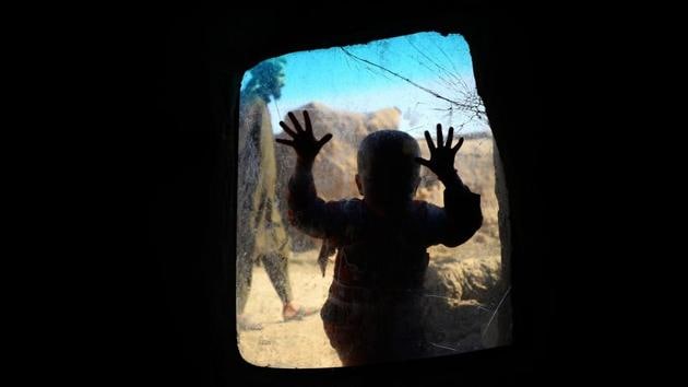 An internally displaced Afghan child looks on from a window in her temporary home at a refugee camp on the outskirts of Herat. (Hoshang Hashimi / AFP)