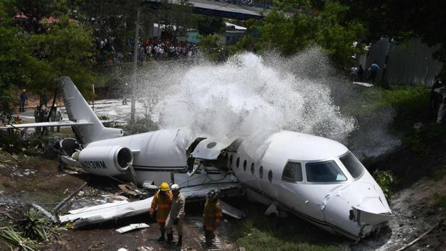 Firefighters spray foam on the wreckage of a plane, after it went off the runway at Toncontin International airport and collapsed over a busy boulevard in Tegucigalpa, Honduras. (Orlando Sierra / AFP)