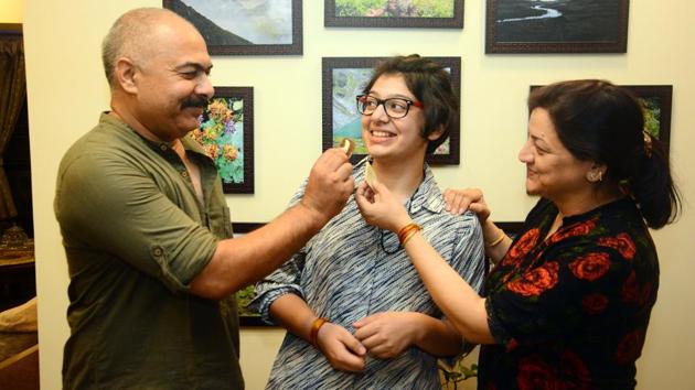 Aastha Tiwary with her parents at her home on Saturday. She topped the CBSE board exams in the city, scoring 98.4 per cent in the Humanities stream.(SHANKAR NARAYAN/HT PHOTO)