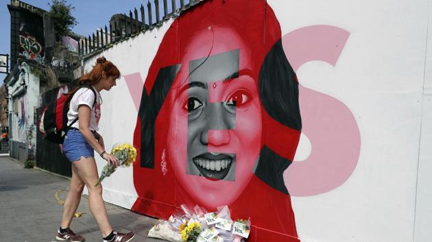 A woman places flowers by a mural showing Savita Halappanavar, a 31-year-old Indian dentist who had sought and been denied an abortion before she died after a miscarriage in a Galway hospital, with the word YES over it, in Dublin, Ireland, on the day of a referendum on the 8th amendment of the constitution.(AP)