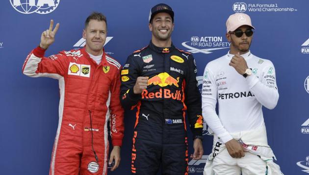 Pole position winner Red Bull driver Daniel Ricciardo of Australia (C) celebrates flanked by second placed Ferrari driver Sebastian Vettel of Germany (L) and third placed Mercedes driver Lewis Hamilton of Britain at the end of the qualifying session for Sunday's Formula One Monaco Grand Prix on Saturday.(AP)