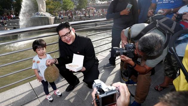 Howard, an Australian-Chinese impersonating North Korean leader Kim Jong Un, poses with a durian and a box of chicken rice at the Merlion Park in Singapore May 27, 2018.(REUTERS)