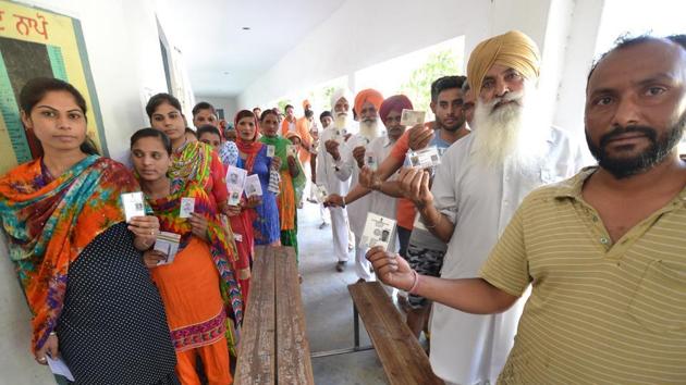 Voters with their ID cards outside a polling booth during in Lohian on Monday. (Pardeep Pandit/HT )