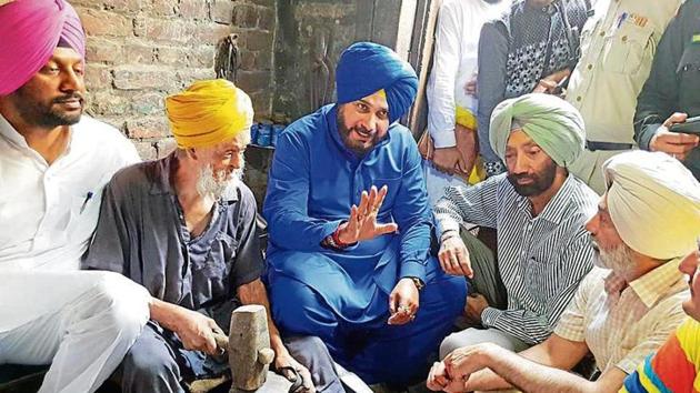 Punjab tourism and culture minister Navjot Singh Sidhu visiting an artisan who makes traditional brass and copper utensils at Jandiala Guru in Amritsar on Sunday.(HT Photo)