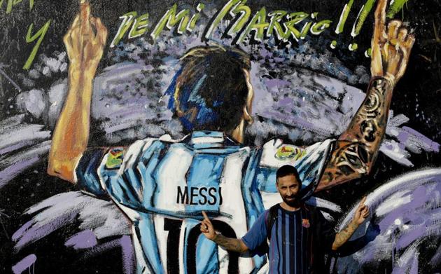 In this April 18, 2018 photo, Alejandro Daniel Fernandez poses for a photo by a mural of his childhood friend, Lionel Messi, that reads in Spanish "From my neighborhood!" in La Bajada, Rosario, Argentina. Fernandez said Messi's family had always helped him, including living with the family for a while, and that he remains friends with Lionel and his brother who all play soccer together when in town.(AP)