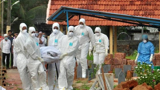 Doctors and relatives wearing protective gear carry the body of a Nipah victim during his funeral at a burial ground in Kozhikode, Kerala.(Reuters)