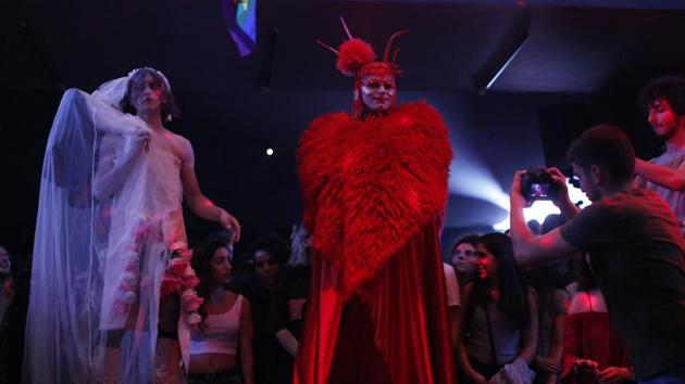 At the ball, Melanie Coxxx mesmerized the audience with a red furry coat and cap. To cheers, she pulled off her big reveal: dark painted veins running over her skull, winning second prize in the “Club Kid” category. “Keep your head up, nothing lasts forever. Here’s to the damned, to the lost and forgotten,” Elias lip-synced after a quick change. The crowd erupted as he raised a “Queer Power” banner. (Hassan Ammar / AP) At the ball, Melanie Coxxx mesmerized the audience with a red furry coat and cap. To cheers, she pulled off her big reveal: dark painted veins running over her skull, winning second prize in the “Club Kid” category. “Keep your head up, nothing lasts forever. Here’s to the damned, to the lost and forgotten,” Elias lip-synced after a quick change. The crowd erupted as he raised a “Queer Power” banner. (Hassan Ammar / AP)