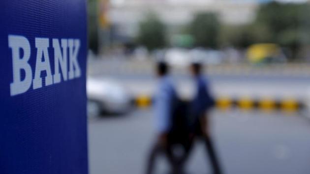 Commuters walk past a bank sign along a road in New Delhi. Services are likely to be affected on Wednesday and Thursday as the bank strike begins across India.(Reuters File Photo)