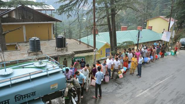 Residents queue up to collect drinking water from a tanker in Shimla.(PTI Photo)