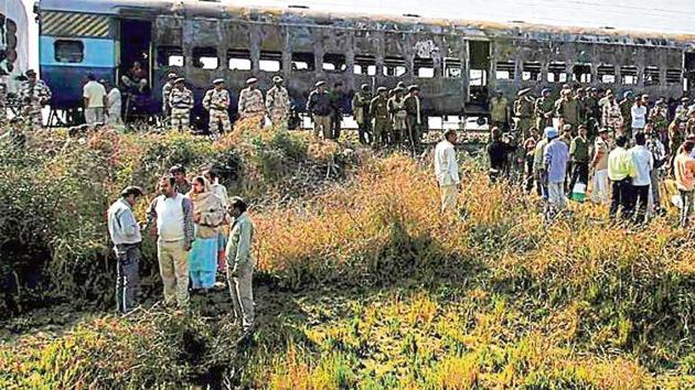 People gather near the burnt bogies of the Samjhauta Express that caught fire following explosions near Panipat in Haryana in 2007.(PTI File Photo)