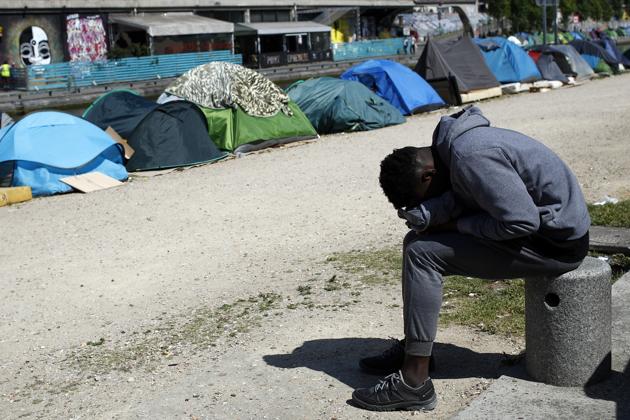 A migrant takes a nap near tents alongside the Canal Saint-Martin in Paris. City Hall says it has spent 30 million euros since 2015 helping refugees, bolstering state aid, as well as 80 million euros each year on isolated minors. “This is an issue of dignity,” said Pierre Henry, head of an aid group, France Terre D’Asile. “Street camps should not exist in our country.” (Francois Mori / AP) A migrant takes a nap near tents alongside the Canal Saint-Martin in Paris. City Hall says it has spent 30 million euros since 2015 helping refugees, bolstering state aid, as well as 80 million euros each year on isolated minors. “This is an issue of dignity,” said Pierre Henry, head of an aid group, France Terre D’Asile. “Street camps should not exist in our country.” (Francois Mori / AP)