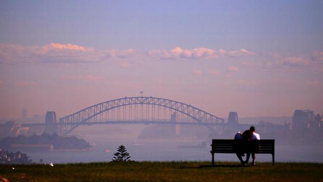 A couple spend their evening in a park by the Sydney Harbour which was covered in smoke from hazard reduction burns of bushland in Australia on May 29, 2018. (David Gray / REUTERS) A couple spend their evening in a park by the Sydney Harbour which was covered in smoke from hazard reduction burns of bushland in Australia on May 29, 2018. (David Gray / REUTERS)