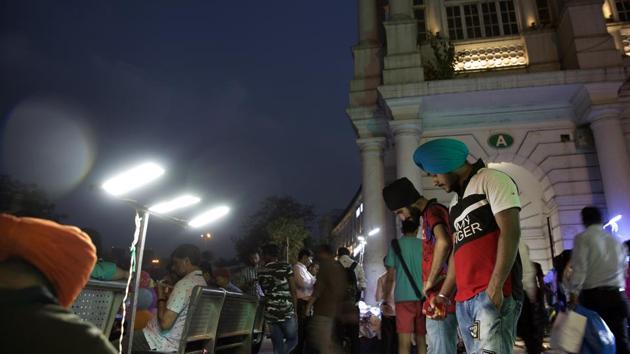 Customers look at clothing displayed at a stall at Connaught Place in New Delhi.(Ruhani Kaur/Bloomberg)