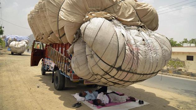 Men sleep in the shadow of an overflowing cloth container of hay, to be used as animal fodder, on a truck in Ajmer, Rajasthan on May 30, 2018. (Shaukat Ahmed / AFP) Men sleep in the shadow of an overflowing cloth container of hay, to be used as animal fodder, on a truck in Ajmer, Rajasthan on May 30, 2018. (Shaukat Ahmed / AFP)