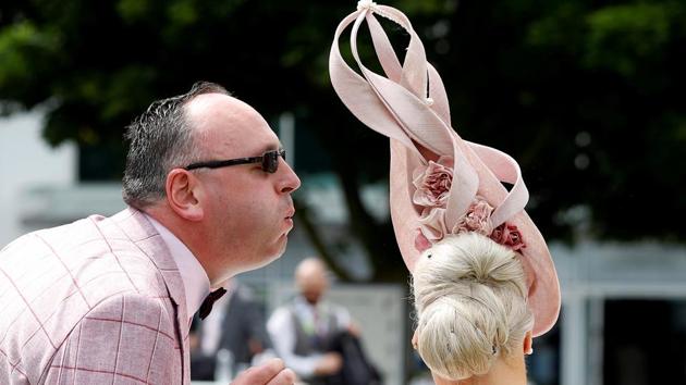 A racegoer blows at an insect perched on a woman’s hairdo during Ladies Day at The Investec Derby Festival. (REUTERS / Peter Nicholls )