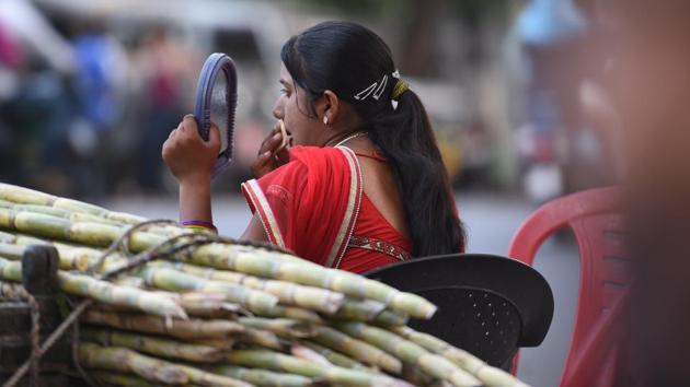 A woman vendor touches up her make-up near her sugarcane juice stall. An estimate of 800-1000 women hailing from Rajasthan’s Tonk district come to Kota during the summer to run these stalls.  What is unusual is their emphasis on going the extra mile while dressing up to serve their customers. (Raj K Raj / HT Photo) 