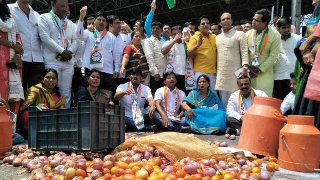 Farmers protest by spilling milk and vegetables at Khed Shivapur in Pune on Friday.(HT Photo)