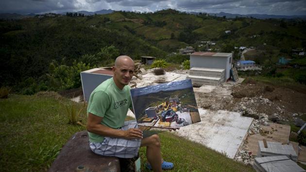 Rafael Reyes sits at his property in the San Lorenzo neighbourhood of Morovis holding a photo of him taken on October 7, 2017 amid his rubbled wooden home. The 41-year-old father and husband who collects Social Security has been living with his in-laws and said he plans to begin rebuilding work with FEMA’s $31,000 assistance. Instead of wood, Reyes said this time he’ll build with stones. (Ramon Espinosa / AP)