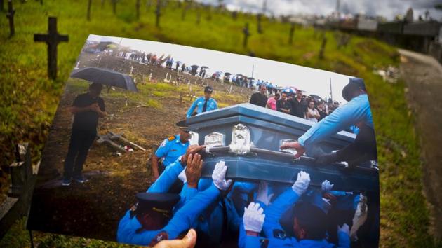AP photographer Ramon Espinosa holds a photo taken on September 29, 2017 showing police lifting the coffin of an officer killed during the hurricane while crossing a river. Eight months since, local police still lack about a dozen officers due to resignations and retirements. Puerto Rico’s bankruptcy has frozen promotions, salaries, new hires and even shut some police academies. (Ramon Espinosa / AP)