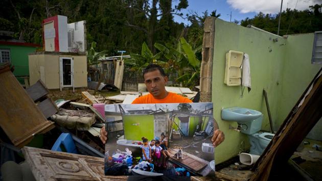 Arden Dragoni holds a photo showing him with his family members in the remains of his destroyed home, which remains in shambles in Toa Baja, Puerto Rico. The unemployed construction worker and security guard is currently separated as his wife and his children live in a FEMA subsidized apartment. “The hurricane brought us many calamities but my lesson was to value my family from my heart,” Dragoni said. (Ramon Espinosa / AP)