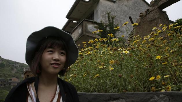 Huang Dan, a 22-year-old student visited on a recent weekend to photograph the beauty of human structures subsumed by roots, rain, vines and wind. “It feels like this place belonged to nature from the very beginning, and the old invaders finally left, and nature finally made it back,” she said. (Sam McNeil / AP) Huang Dan, a 22-year-old student visited on a recent weekend to photograph the beauty of human structures subsumed by roots, rain, vines and wind. “It feels like this place belonged to nature from the very beginning, and the old invaders finally left, and nature finally made it back,” she said. (Sam McNeil / AP)