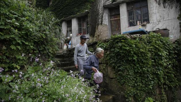 Lin Fazhen (wearing a cap), 60, leaves his home with a neighbour. In Houtouwan’s heyday, Lin ran a small store in 1984 catering to fishermen. He sold cigarettes, alcohol, fishing supplies, canned food, biscuits and fruit that he imported on boats from the mainland. “They went to the sea when the boats were sailing, and they came back when it got windy. They played mahjong,” he said. (Fu Ting / AP) Lin Fazhen (wearing a cap), 60, leaves his home with a neighbour. In Houtouwan’s heyday, Lin ran a small store in 1984 catering to fishermen. He sold cigarettes, alcohol, fishing supplies, canned food, biscuits and fruit that he imported on boats from the mainland. “They went to the sea when the boats were sailing, and they came back when it got windy. They played mahjong,” he said. (Fu Ting / AP)