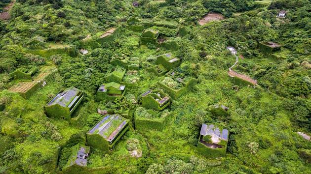 A blanket of greenery covers the ghost town, which is perched atop cliffs looking west into sea mists obscuring the horizon. Abandoned homes ravaged by weather and creeping vines stand silent but for the surf, the whine of mosquitoes, and birdsong. This is Houtouwan — “Back Bay” in Mandarin — an abandoned fishing village engulfed by nature on the far-eastern island of Shengshan, off the coast of Shanghai. (Johannes Eisele / AFP) A blanket of greenery covers the ghost town, which is perched atop cliffs looking west into sea mists obscuring the horizon. Abandoned homes ravaged by weather and creeping vines stand silent but for the surf, the whine of mosquitoes, and birdsong. This is Houtouwan — “Back Bay” in Mandarin — an abandoned fishing village engulfed by nature on the far-eastern island of Shengshan, off the coast of Shanghai. (Johannes Eisele / AFP)