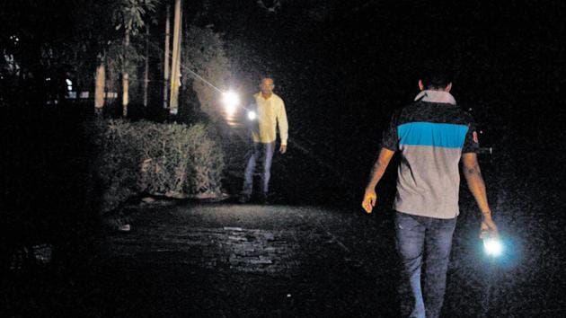 People use their mobile flashlights while walking on the road in Gurugram.(Yogendra Kumar/HT Photo)