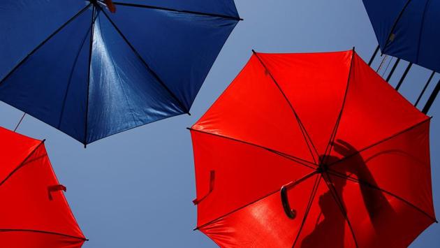 A worker arranges coloured umbrellas hanging over a street in preparation for a music festival at the weekend, in Zabbar, Malta. (Darrin Zammit Lupi / REUTERS)