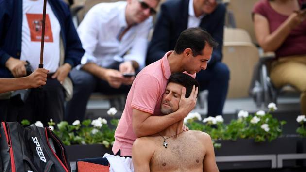 Novak Djokovic (C) receives treatment from a trainer between games against Italy's Marco Cecchinato during their men's singles quarter-final match on day ten of The Roland Garros 2018 French Open tennis tournament in Paris, France. (Eric Feferberg / AFP)