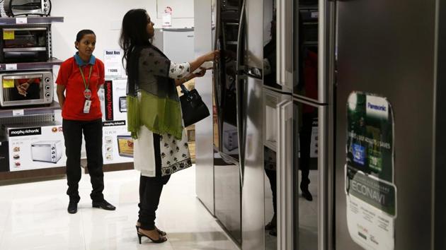 A customer inspects a refrigerator on display as a sales assistant looks on at a Croma electronics megastore.(Bloomberg)