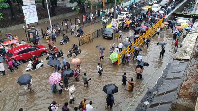 People make their way through a waterlogged road in Parel. Owing to water logging in parts of central Mumbai like Dadar east, Parel, Sion, Kings Circle and surroundings, traffic was hit badly and diversions were implemented to prevent snarls. (Pratik Chorge / HT Photo)