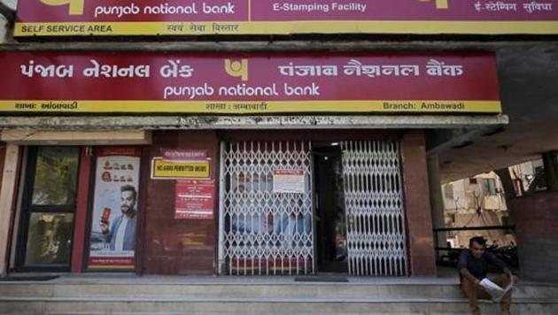 A man reads a newspaper outside a branch of Punjab National Bank (PNB) in Ahmedabad.(Reuters File Photo)