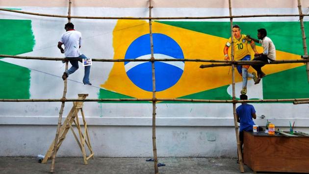 A painter applies finishing touches to an image of Neymar on a large Brazilian flag on a road side wall. (REUTERS)