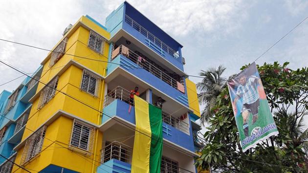 Fans hang a large flag from a residential building next to a banner featuring Argentina's Lionel Messi. (REUTERS)