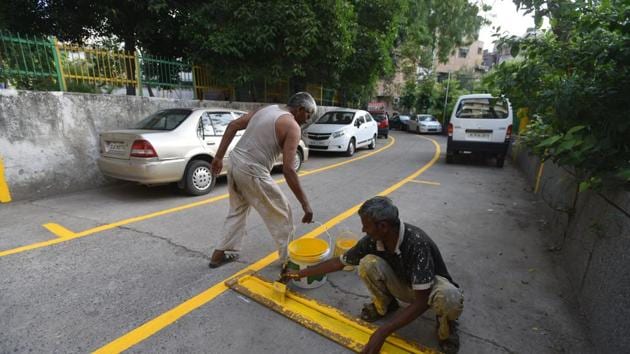 A labourer paints a line on a road for making a boundary for parking at Lajpat Nagar II in New Delhi , India, on Monday, June 11, 2018.(HT Photo)