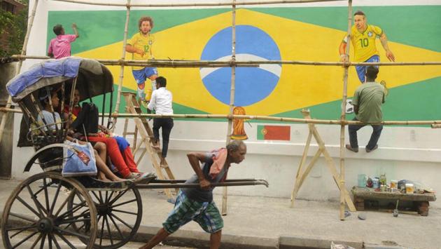 A hand-rickshaw puller moves past a wall painted with graffiti of Brazilian football players Neymar and Marcelo. (HT PHOTO)