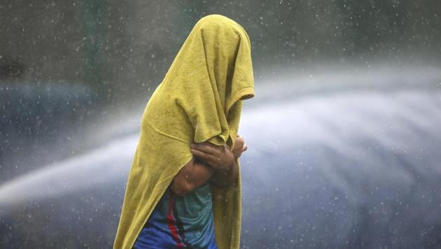 An unidentified player of the Afghan cricket team covers himself with a towel as he runs for shelter during sudden rains at a training session ahead of the team’s maiden test match against India in Bangalore. (Aijaz Rahi / AP)