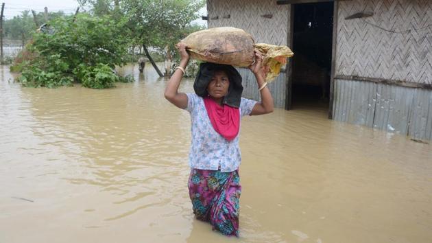 A resident carries belongings over her head on a flooded street during heavy rain showers in Mogpara village, some 137 km south of Agartala, Tripura. (Arindam Dey / AFP)