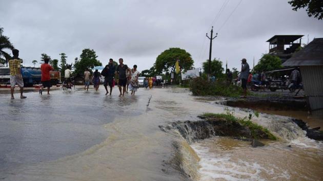 People wade through a flooded National Highway 37 at Bokakhat in Golaghat district of Assam on Thursday. (HT Photo)(HT Photo)