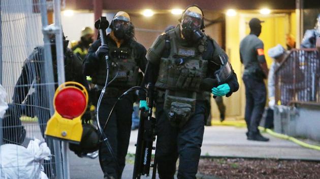 German police officers in protective gear leave an apartment building during an operation in Cologne.(AP Photo)