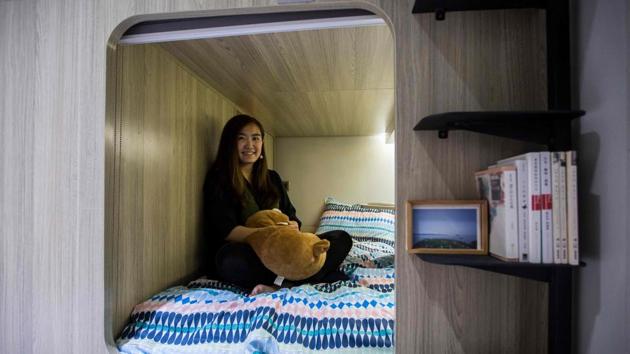 Michelle Chau sits on her bed in her rented living space in a co-sharing building in Hong Kong’s Mong Kok district. As housing prices spiral, young professionals in Hong Kong are living in ever-shrinking spaces, with box-like “nano-flats” and co-shares touted as fashionable solutions. (Isaac Lawrence / AFP)