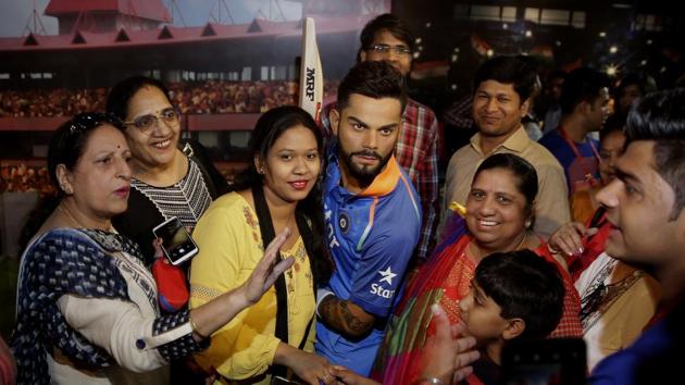 Visitors pose for photographs next to a wax figure of Indian cricket captain Virat Kohli during its unveiling at Madame Tussauds wax museum in New Delhi.(AP)