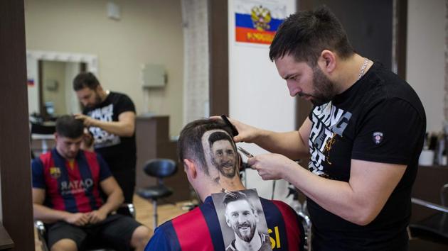 A hairdresser creates a tattoo of Argentinian football player Lionel Messi on the head of a football fan in Novi Sad, Serbia, on June 10, 2018(AFP)