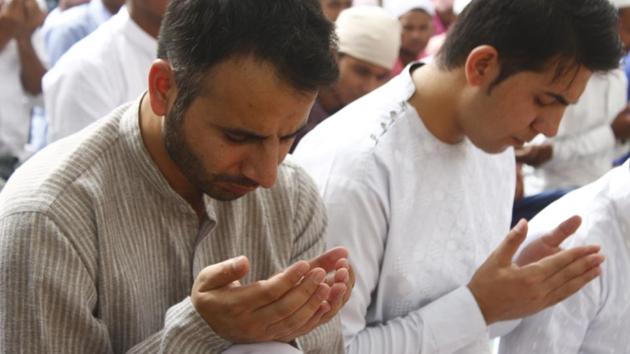 People raise their hands for blessings during morning prayers in Gurugram. (Yogendra Kumar / HT Photo)