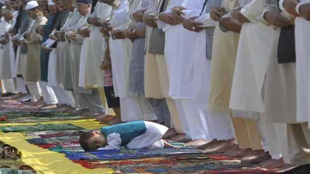 A little boy sneaks a glance as elders pray at an Eidgah in downtown Srinagar. (Waseem Andrabi / HT Photo)