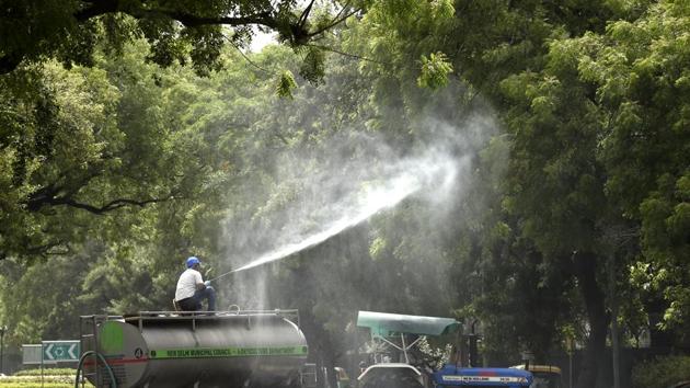 Employees of New Delhi Municipal Council horticulture department spray water over trees to curb air pollution by combating accumulated dust, near Vigyan Bhawan in New Delhi, on Friday.(Arvind Yadav/HT Photo)