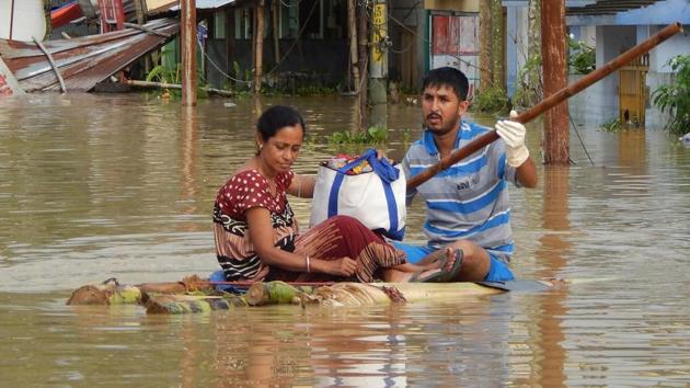 People sit on a makeshift raft after a heavy downpour at Kailashahar in Tripura. More than 70,000 people have been displaced from their homes due to last week’s incessant rains.(AFP)